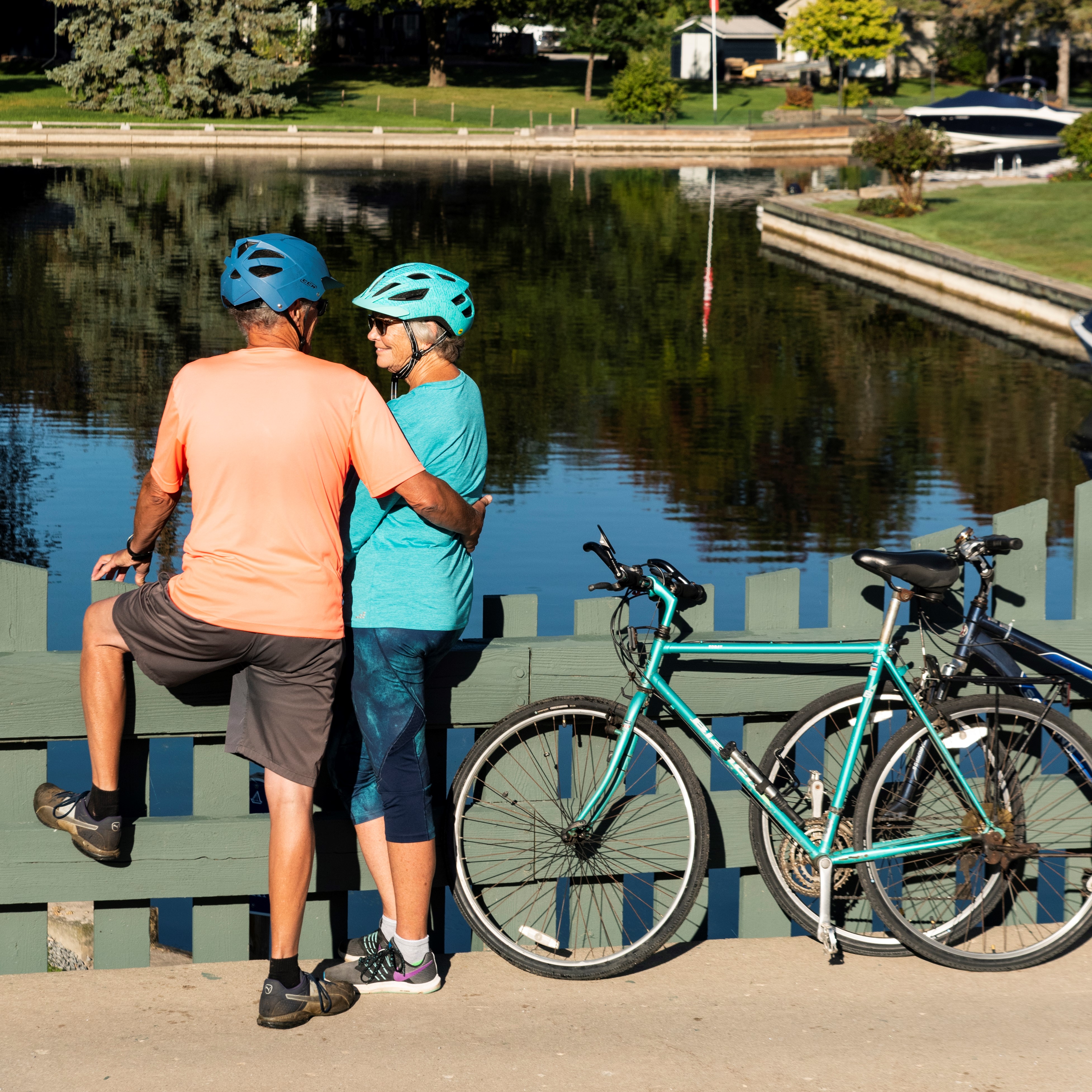 man and women standing on bridge next to bicycle looking at water