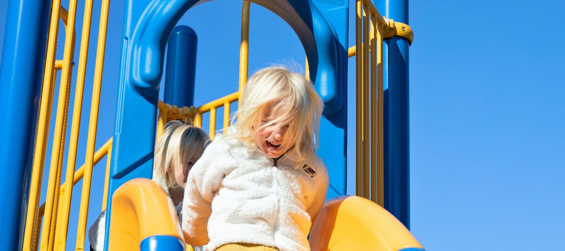 Two girls going down a playground slide