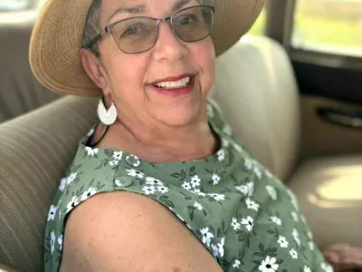 Woman named Jane Lee sitting in a car wearing a hat and green dress